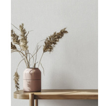 Decoratief behang met textielpatroon en vaas met siergras op een houten tafel