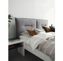 Bed met grijze hoofdeinde, wit nachtkastje en gestreept beddengoed voor een heldere slaapkamerambiance