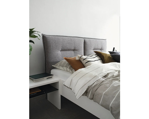 Bed met grijze hoofdeinde, wit nachtkastje en gestreept beddengoed voor een heldere slaapkamerambiance