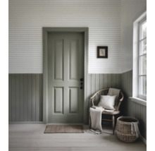 Lichte entree met deur, houten stoel, mand en wandpanelen.