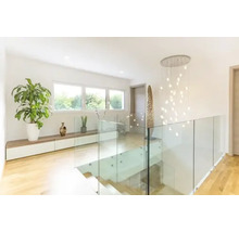 Lichte hal met trap, glazen balustrade, kamerplanten en hanglamp