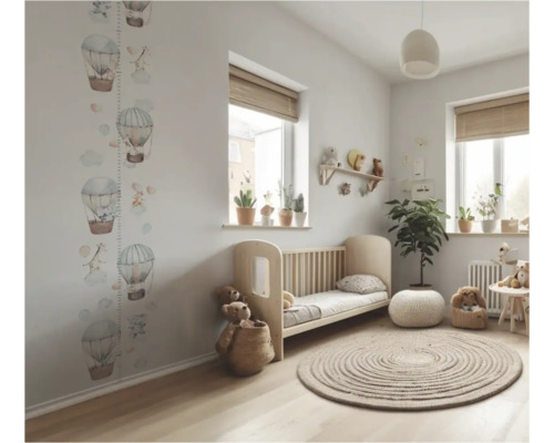 Lichte kinderkamer met ledikant, rond vloerkleed, kamerplanten en muursticker met luchtballonnen