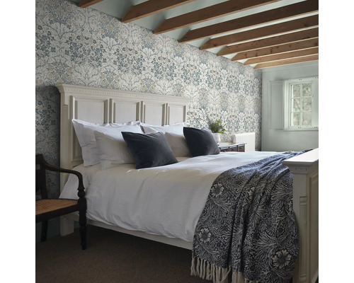 Slaapkamer met behang met motief, bed en houten balken in het zicht.