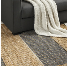 Gedetailleerd beeld van een gestreept vloerkleed onder een bank met een deken.