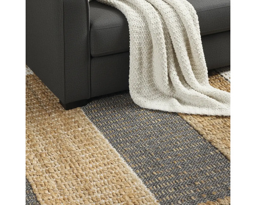 Gedetailleerd beeld van een gestreept vloerkleed onder een bank met een deken.