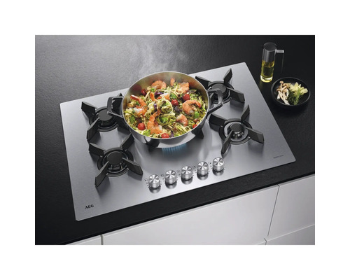 AEG gaskookplaat met voedsel in een pan, olie en champignons op een aanrecht