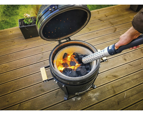 Keramische barbecue met gloeiende houtskool wordt aangestoken met een aanmaakblokjesstarter