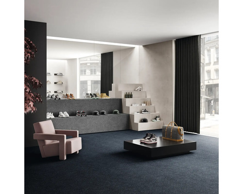 Verkoopruimte met schoenen op trappen en plateaus, fauteuil en vloerbedekking