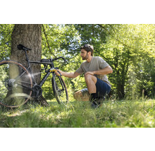 Man reinigt fiets met draagbare reiniger in de buitenlucht