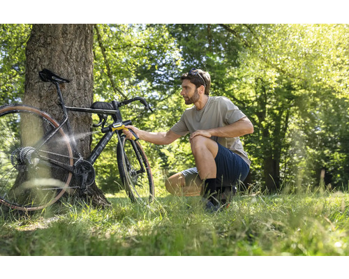 Man reinigt fiets met draagbare reiniger in de buitenlucht