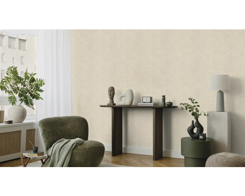 Lichte, gestructureerde behang in een woonkamer met fauteuil, tafel en decoratie.