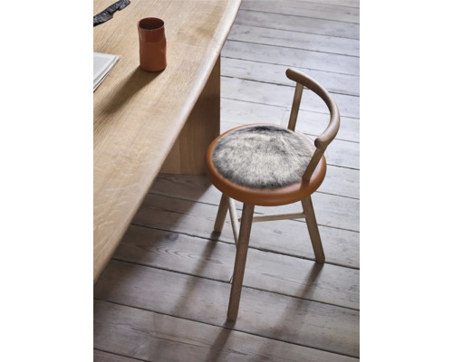 Houten stoel met ronde zitting en vachtkleed naast houten tafel