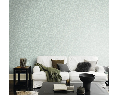 Woonkamer met witte bank en muur met bladerbehang