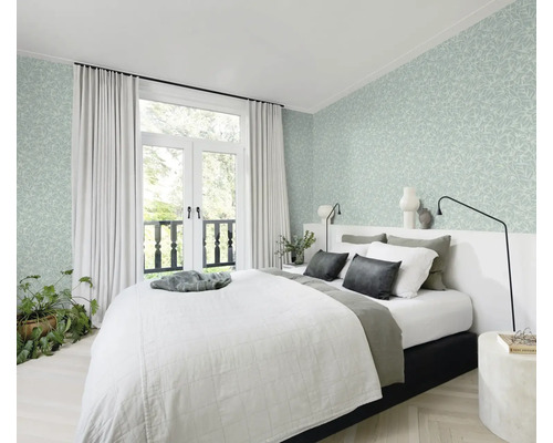 Slaapkamer met bed, gordijnen en bloemenbehang