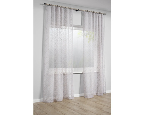 Transparant wit gordijn met verticaal golfpatroon voor een licht raam in een lichte en modern ingerichte kamer.