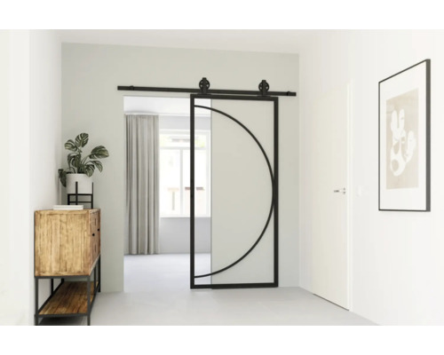 Interieur van een gang met een schuifdeur van glas en metaal met een cirkelvormig ontwerp, een houten kast met een plant en een ingelijste foto aan de muur