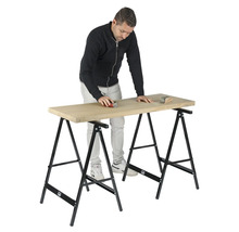 Man schuurt houten plank op twee schragen.