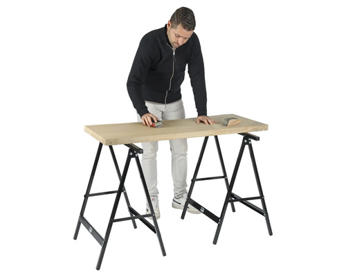 Man schuurt houten plank op werkbank met schragen