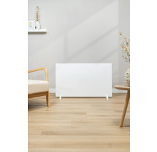 Scene met een wit verwarmingspaneel op een lichte houten vloer, naast een fauteuil en een bijzettafel.