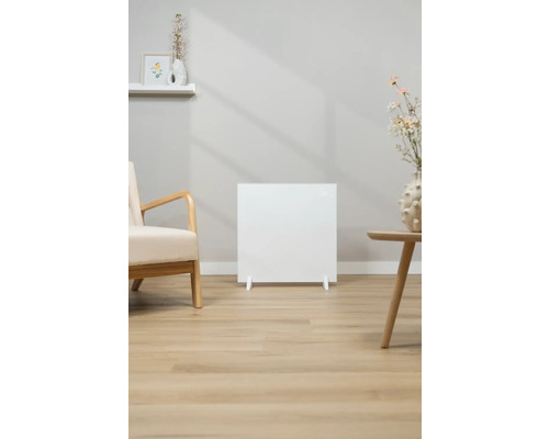 Witte radiator in de woonkamer naast een fauteuil en een bijzettafel.