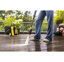 Hogedrukreiniger in gebruik op een houten terras met plantenbakken.