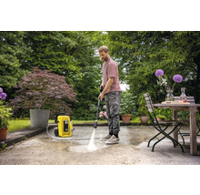 Man reinigt terras met hogedrukreiniger in de tuin.