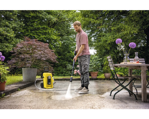 Man reinigt terras met hogedrukreiniger in de tuin.