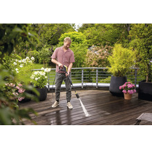 Man reinigt houten terras met hogedrukreiniger in de tuin.