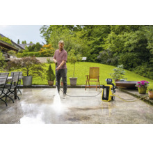 Man reinigt terras met hogedrukreiniger in de tuin.