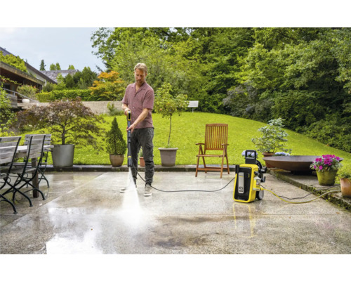 Man reinigt terras met hogedrukreiniger in de tuin.