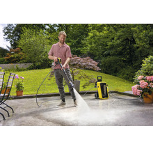 Man reinigt terras met hogedrukreiniger in de tuin.