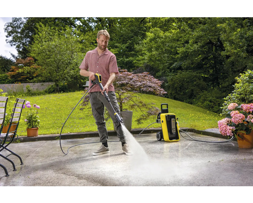 Man reinigt terras met hogedrukreiniger in de tuin.