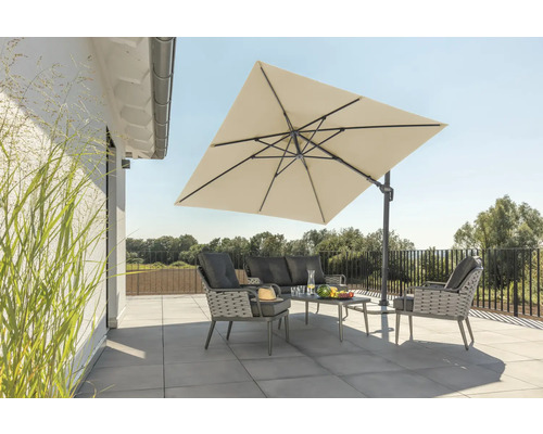 Tuinscene met zweefparasol, bank, fauteuils en tafel op een terras.