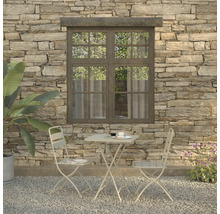 Scène met tuintafel, twee stoelen, servies en plant voor een stenen muur