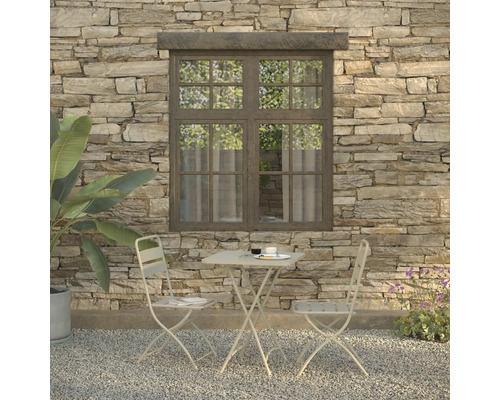 Scène met tuintafel, twee stoelen, servies en plant voor een stenen muur