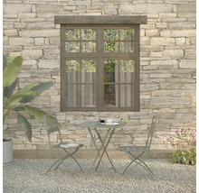 Tuinscène met bistrotafel en twee stoelen voor een stenen muur