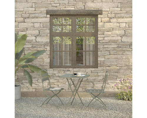 Tuinscène met bistrotafel en twee stoelen voor een stenen muur