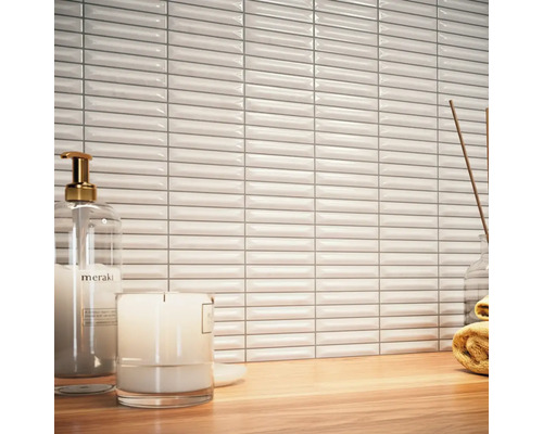 Scene met witte, langwerpige wandtegels, zeepdispenser, kaars en handdoek op een houten tafel