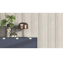 Decoratief interieur met plant, lamp en ladekast tegen een gemusterde wand