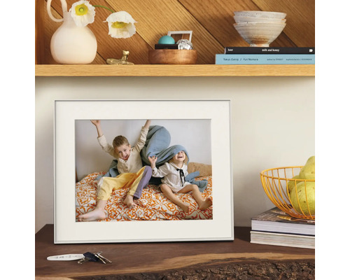 Witte fotolijst met passe-partout, geplaatst op een houten dressoir met decoratie.