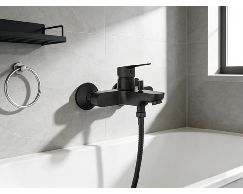 Zwarte badkraan met handdouche en badkameraccessoires aan de muur boven het bad.