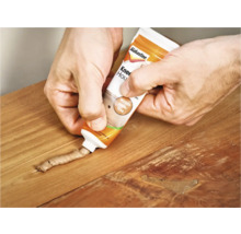 Hand repareert houten tafel met houtrotvuller