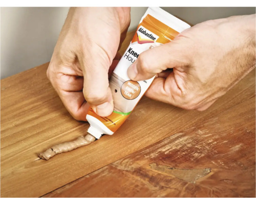 Hand repareert houten tafel met houtrotvuller