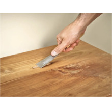 Persoon gebruikt plamuurmes op houten tafel