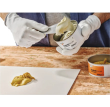 Houtreparatieplamuur wordt met een spatel uit een blik gehaald