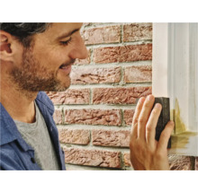 Man schuurt houten frame met schuurblok