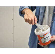 Man neemt plamuur uit een emmer Alabastine gipsplaatvuller.