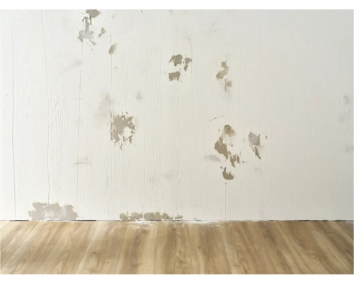 Muur met schade en reparaties op houten vloer