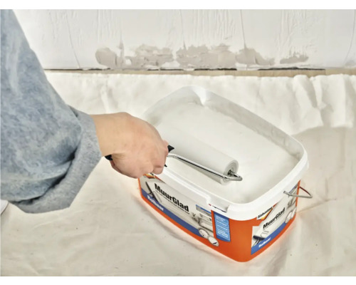 Verf wordt met een verfroller uit een verfemmer opgenomen.