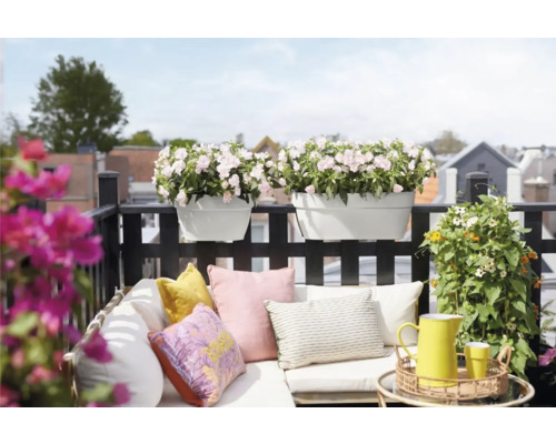 Balkonscène met bloembakken, kussens en decoratie op een balkon.
